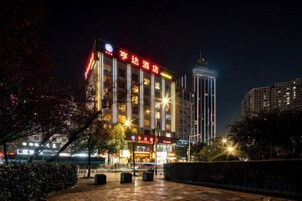 Un hotel moderno con un letrero vertical llamativo, varios pisos y una fachada bien iluminada.