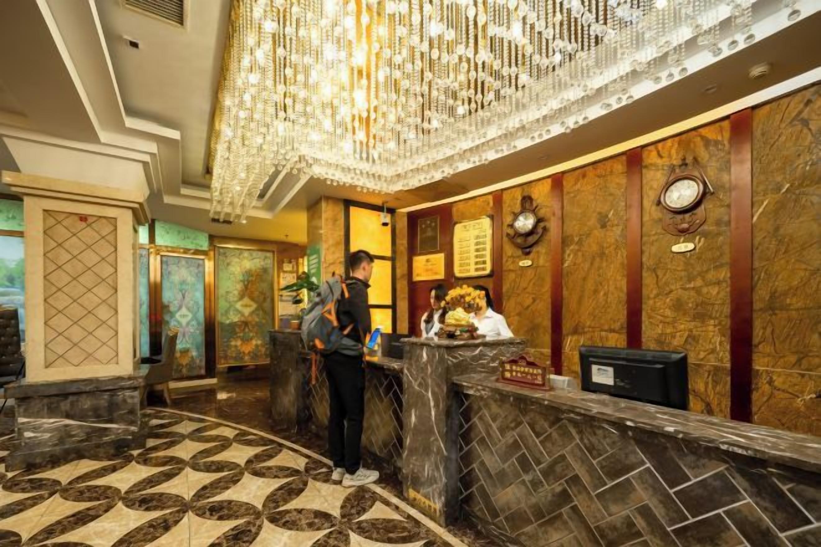 Uma área de recepção de hotel com piso de mármore, balcão de recepção e um lustre.