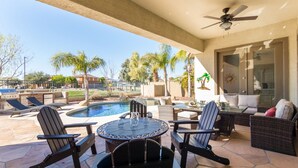 A patio with a pool, outdoor furniture, and a ceiling fan. - Hole in One with pool and putting green! (Goodyear)