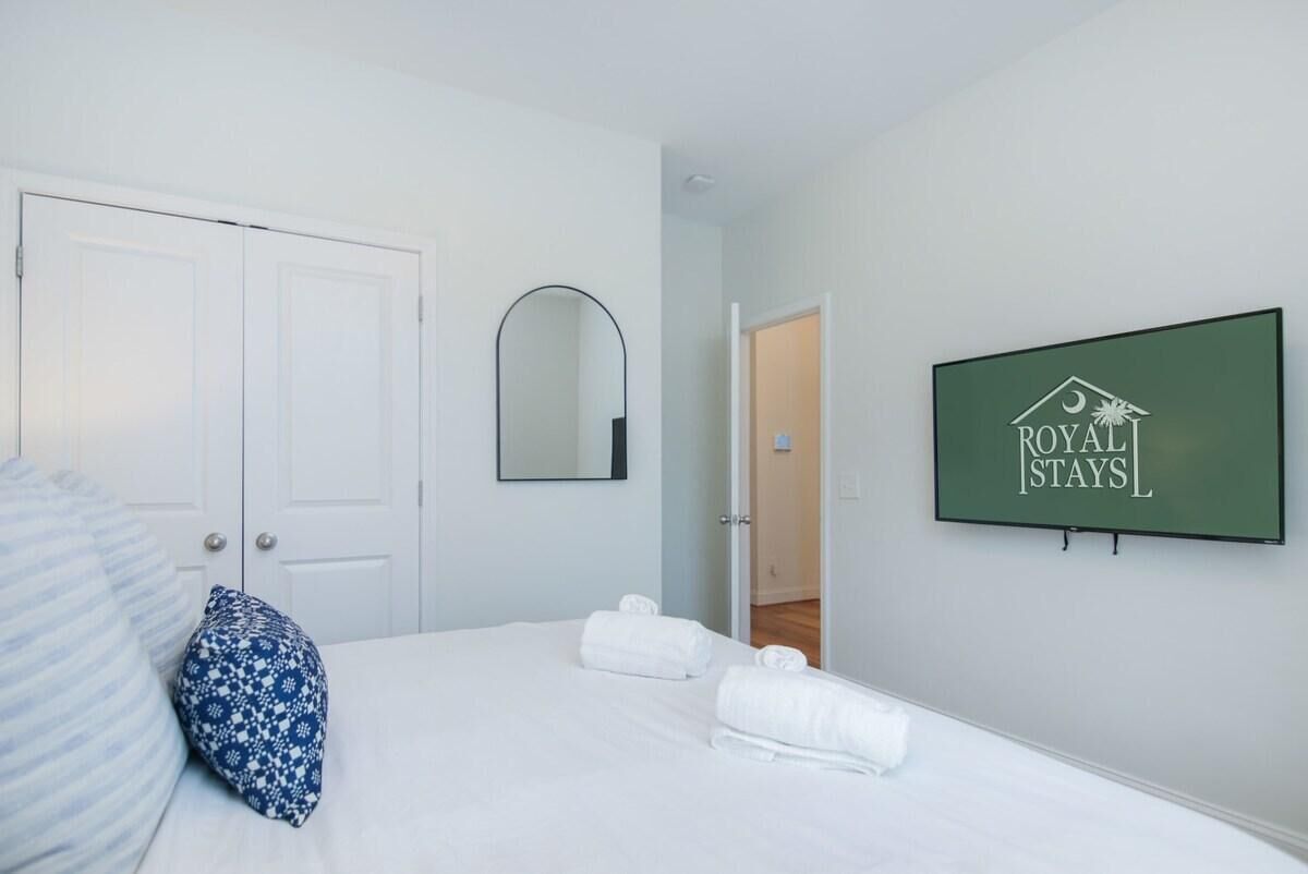 Ein Hotelzimmer mit einem Bett, einer weißen Tür, einem Spiegel und einem gerahmten Schild an der Wand.