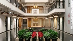 A multi-level hotel lobby with a central seating area, potted plants, and a reception desk. - Shile Hotel (Zhongshan Station) (Zhongshan)