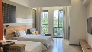 A hotel room with two beds, a TV, a wooden headboard, a balcony with curtains, and a view of greenery. - Shile Hotel (Zhongshan Station) (Zhongshan)