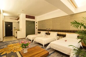 A hotel room with three beds, a wooden coffee table, and a large plant. - Shile Hotel (Zhongshan Station) (Zhongshan)
