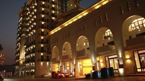A multi-story hotel with a modern design, featuring a prominent entrance with arched windows and a well-lit facade. - Shile Hotel (Zhongshan Station) (Zhongshan)