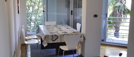 A dining area with a table and chairs, a hanging light fixture, and a view of the outdoors through a glass door.