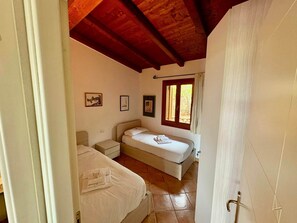 A bedroom with a bed, a bedside table, a nightstand, and a window with curtains.