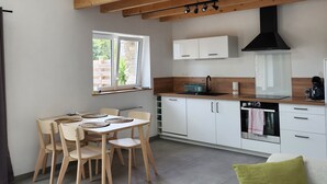 Une cuisine moderne avec des poutres en bois, des armoires blanches et un four encastré.