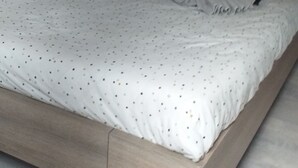 Un grand lit avec un cadre en bois, une literie blanche à motifs pointillés et deux serviettes en forme de cygne.