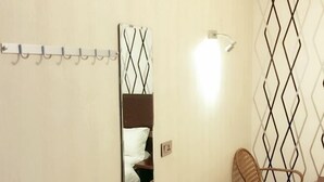 A hotel room with a bed, a chair, a round wicker table, a wall-mounted light, and a decorative mirror. - Shiquan Shimei Hotel (Pingtang)