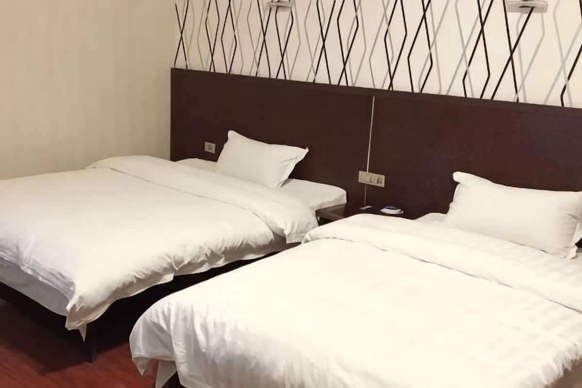 Dos camas individuales con ropa blanca en una habitación de hotel.