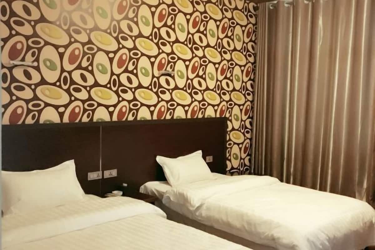 Una habitación de hotel con dos camas, un papel tapiz estampado y una cortina.