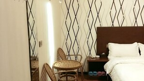 Une chambre d’hôtel avec un lit, une table de chevet, une petite table avec des chaises et un mur décoré de motifs.