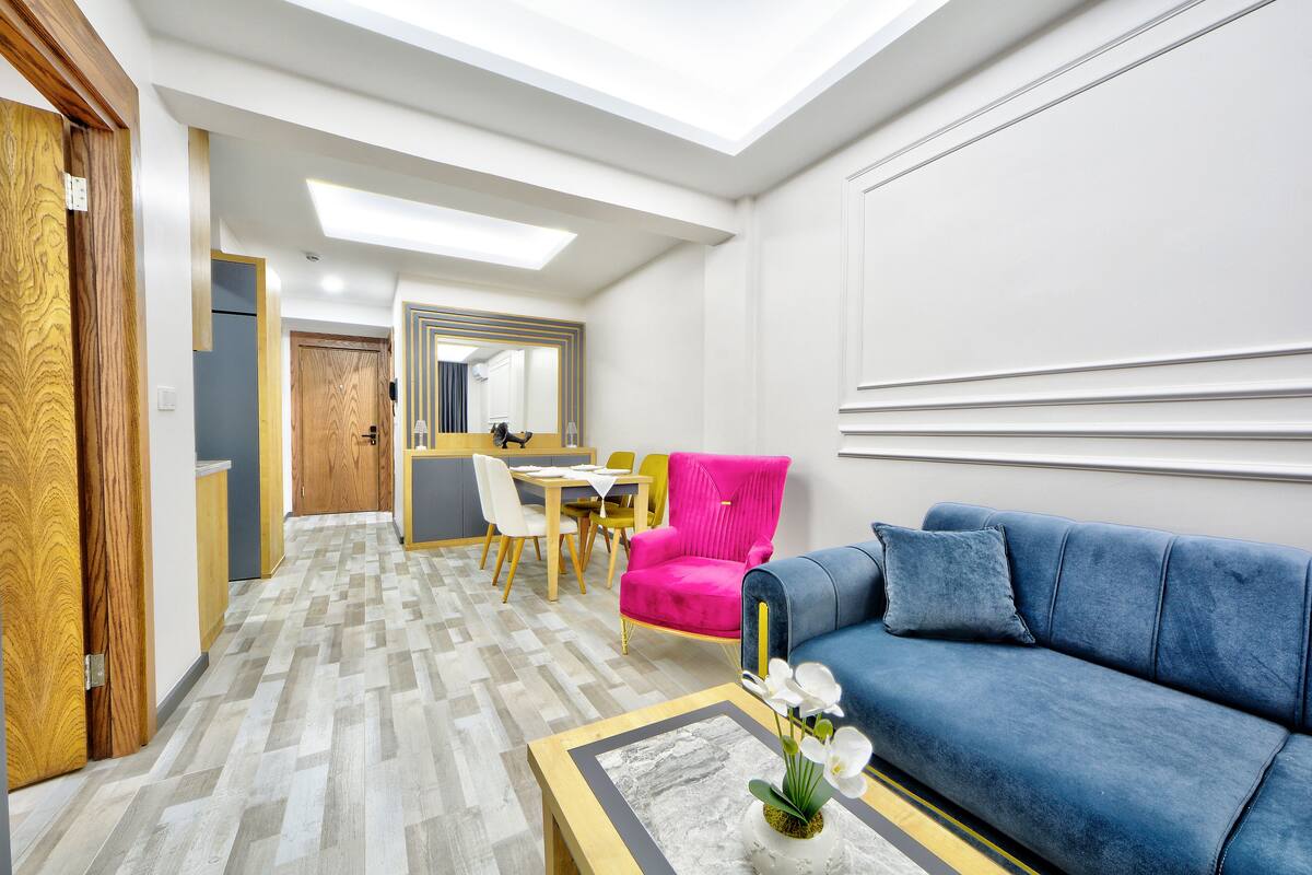 Una sala de estar moderna con un sofá azul, una mesa de centro de madera y un sillón rosa intenso.