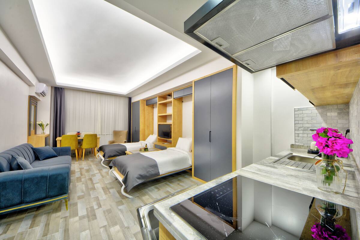 Una habitación de hotel moderna con cama, sof á, kitchenette y zona de comedor.