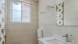 A bathroom with a window, a shower, a toilet, and a sink. - Shanxing Inn (Zhangjiajie)