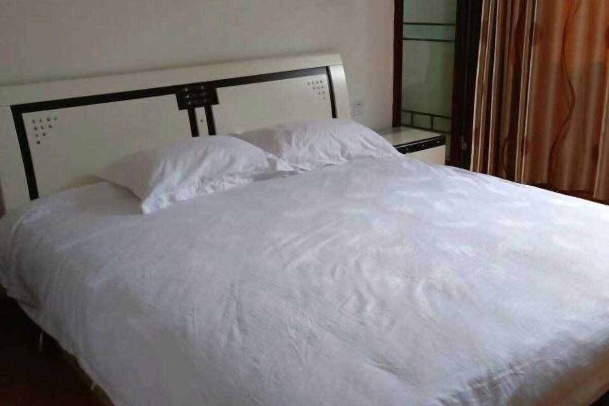 A neatly made bed with white linens in a room with a simple, clean design.