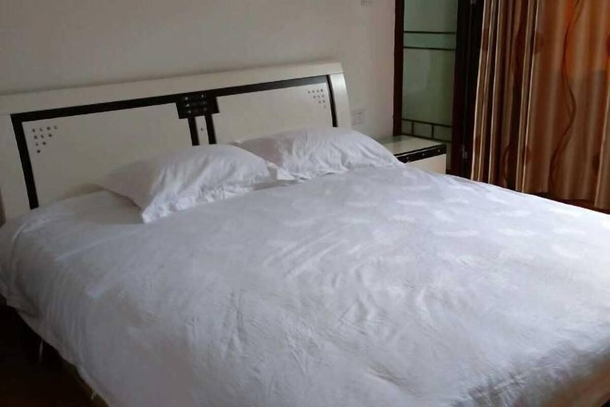 A neatly made bed with white bedding in a room with a simple, clean design.