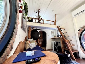Un interior acogedor con una cama entrepiso, una escalera de madera y un comedor.