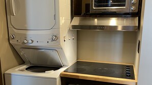 A compact kitchenette with a built-in washer, dryer, microwave, and a small refrigerator.