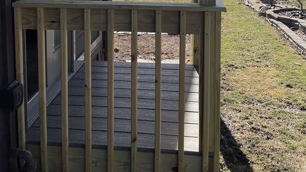 A wooden deck with a glass door leading to a covered porch overlooking a lake.