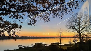 A lakeside view with a sunset, a dock, and a tree.