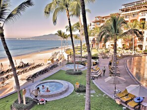 Um resort com área de piscina, espreguiçadeiras e vista para a praia e o oceano.