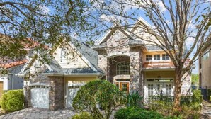 A two-story house with a stone facade, a garage, and a well-maintained garden.