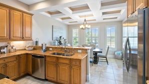 A kitchen with wooden cabinets, a stainless steel dishwasher, and a large island with a sink.