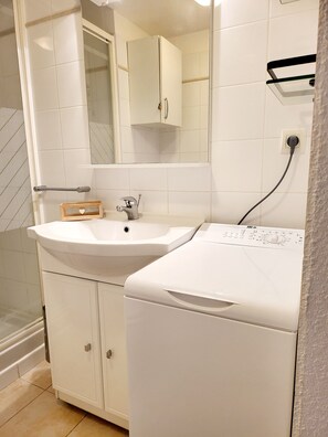 Une salle de bain avec un lavabo, un miroir et un lave-linge.