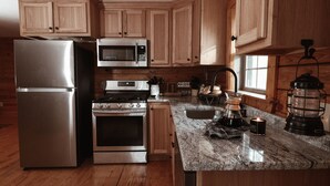 A kitchen with wooden cabinets, stainless steel appliances, a granite countertop, and a coffee maker.