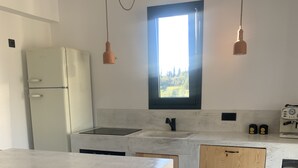 A modern kitchen with a large island, a built-in oven, and a window above the sink. - Porto Cheli, charming house with garden, 5 min. from beach and coves (Porto heli)