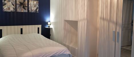 A bedroom with a bed, a nightstand, a lamp, and a wardrobe.