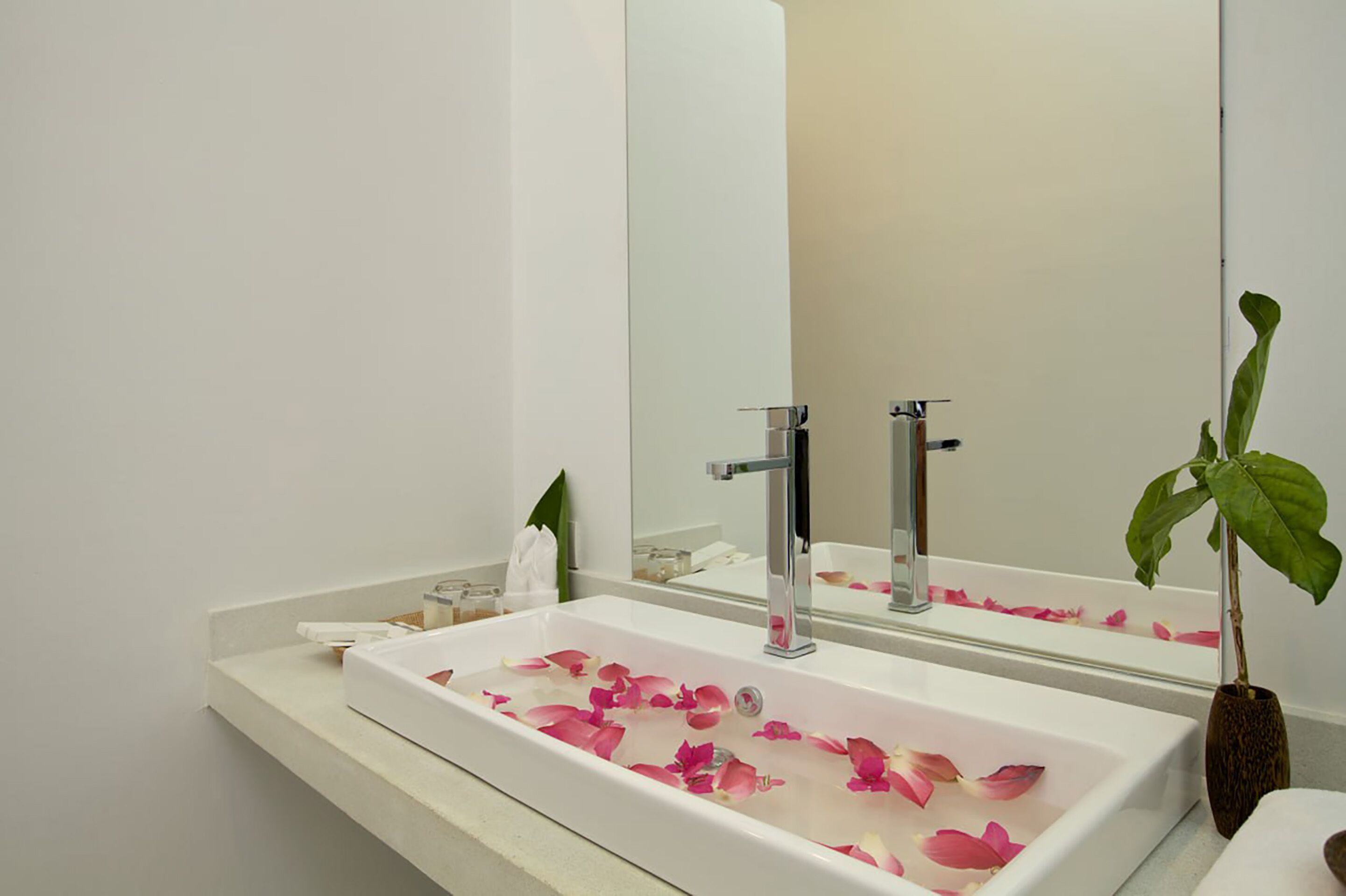 A bathroom with a white sink, chrome faucet, and a mirror above it.