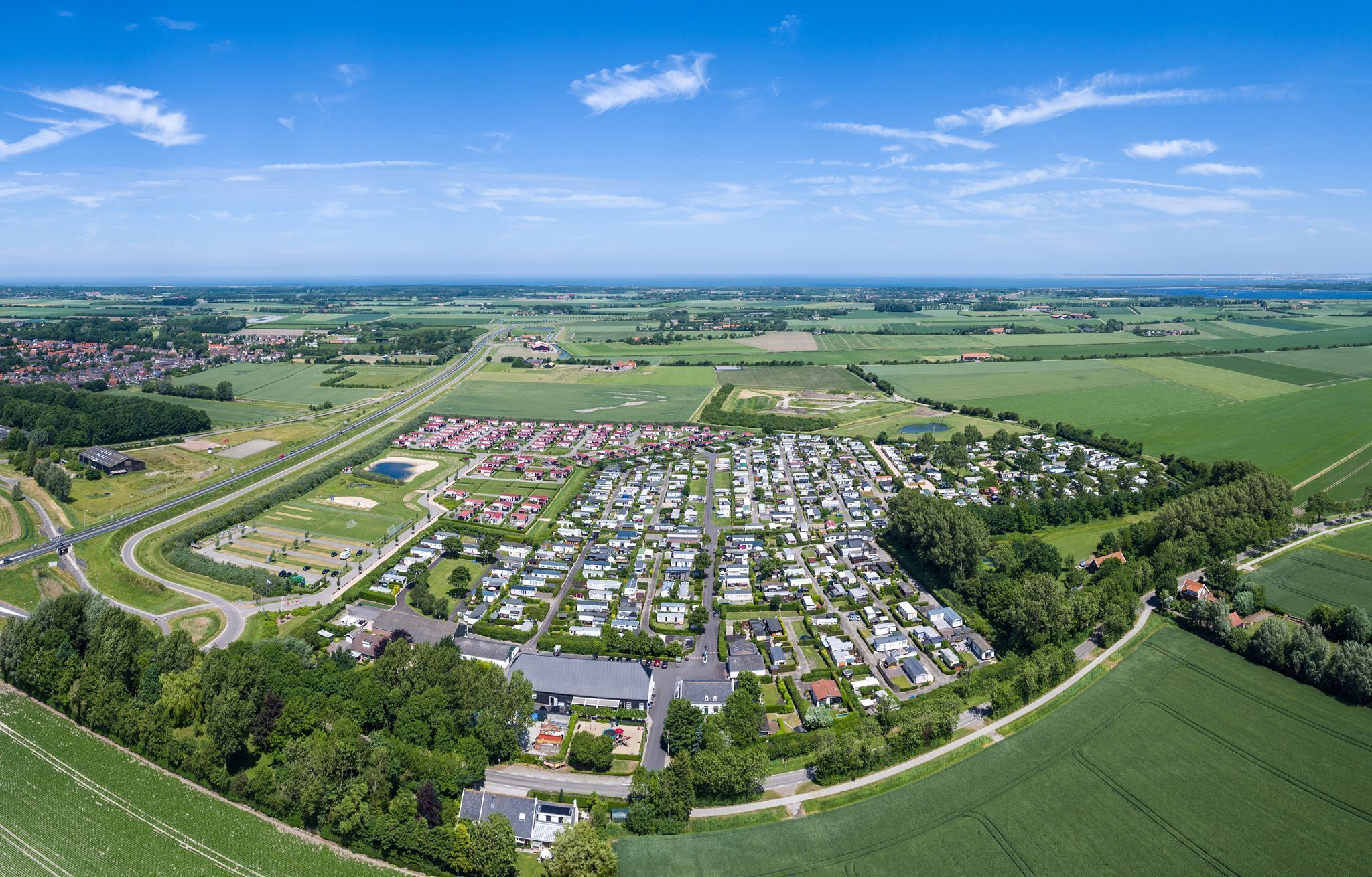 Vista aérea de una zona residencial con casas, caminos y campos verdes.