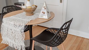 A round dining table with a white macrame table runner, a white vase with dried flowers, a wooden bowl with fruits, and a pyramid-shaped chocolate box. - Guest Favorite Getaway in Lakeview Near Wrigley (Chicago)