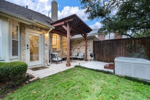 Relax in the backyard's patio area, complete with a sofa, armchairs, and barbecue grill.