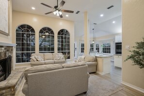 Relax in this inviting living room with a fireplace, sofa, and kitchen area.
