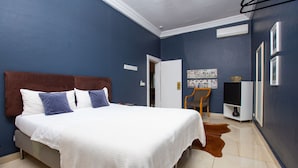 Una camera da letto con un letto grande, una sedia, una televisione e una porta che dà su un'altra stanza.