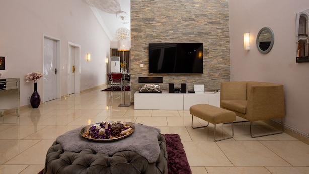Un soggiorno moderno con una parete in pietra, una TV a schermo piatto, un divano e un tavolino decorato con fiori.