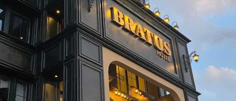 A hotel with a prominent sign reading "BRATUS HOTEL".