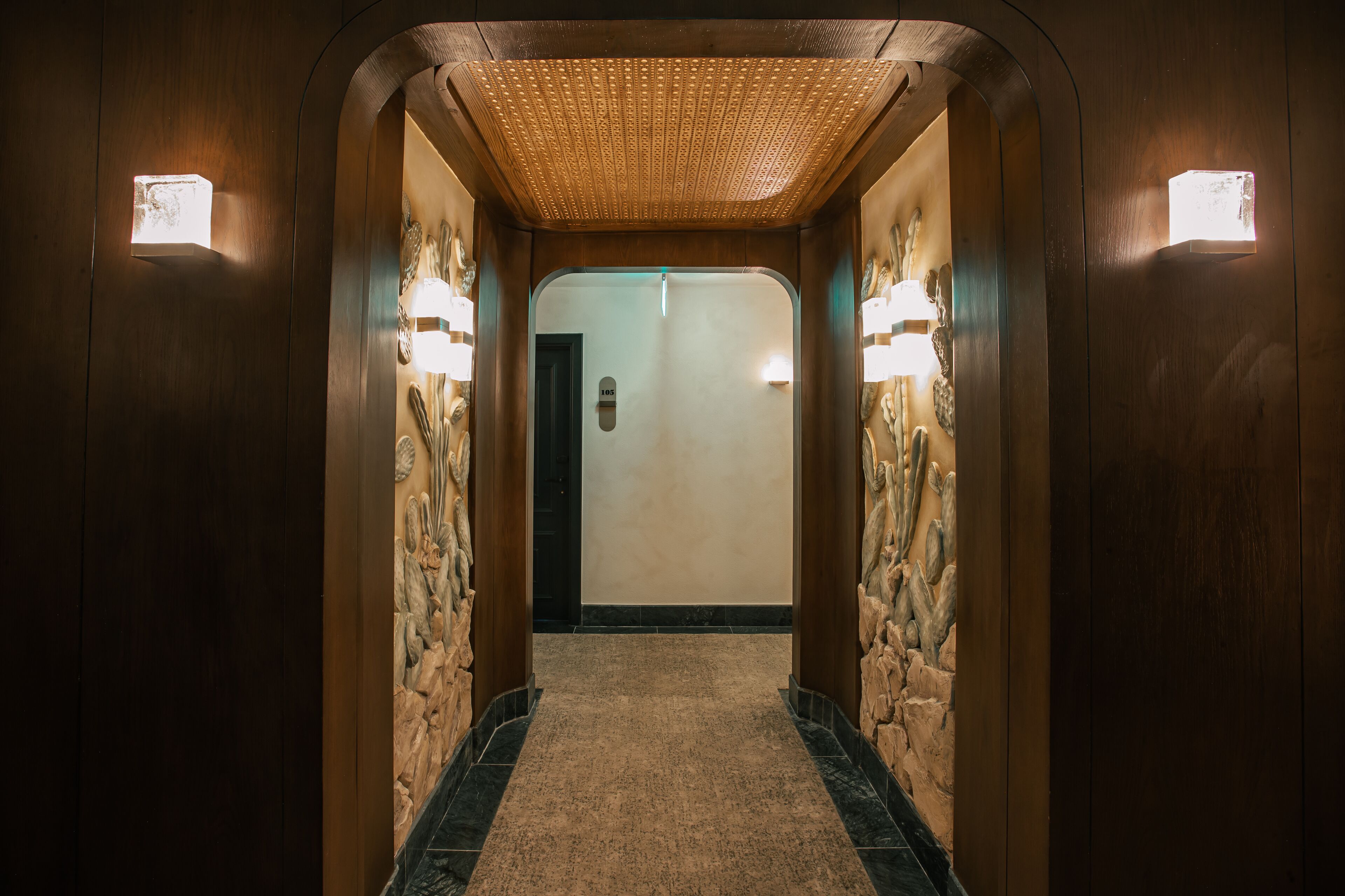 Un pasillo con paredes de madera, techo texturizado y dos luces fijadas a la pared.