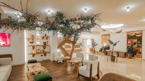 Un área de estar moderna con piso de madera, sofás blancos y una estructura central que recuerda a un árbol.