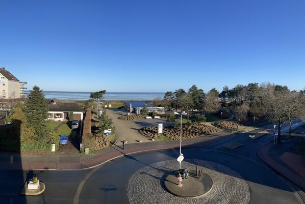 A coastal residential area with a roundabout, a small park with a bench, and a view of the sea.