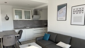 A modern apartment with a dining area, kitchenette, and a living room with a sofa and coffee table.