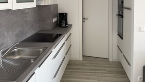 A modern kitchen with stainless steel appliances, a coffee maker, and a built-in oven.