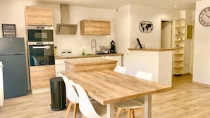 Eine moderne Küche mit Holzausstattung, integriertem Backofen und einem Essbereich mit Holztisch und weißen Stühlen.