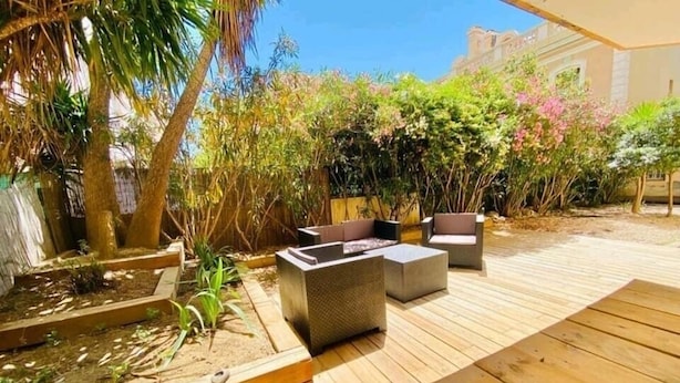 Eine Terrasse im Freien mit Holzboden, einem Holztisch und zwei gepolsterten Stühlen.