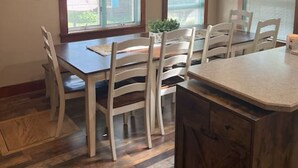 Een eetgedeelte met een houten tafel en stoelen, hanglampen en een uitzicht door grote ramen.