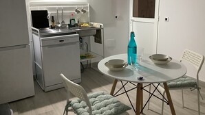 A compact kitchen with a built-in dishwasher, a dining table with two chairs, and a window above the sink. - Penthouse between sea and mountains (CN)