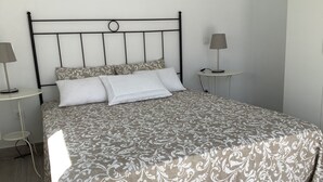 A bed with a patterned bedspread, two bedside tables with lamps, and a wall-mounted light switch. - Penthouse between sea and mountains (CN)